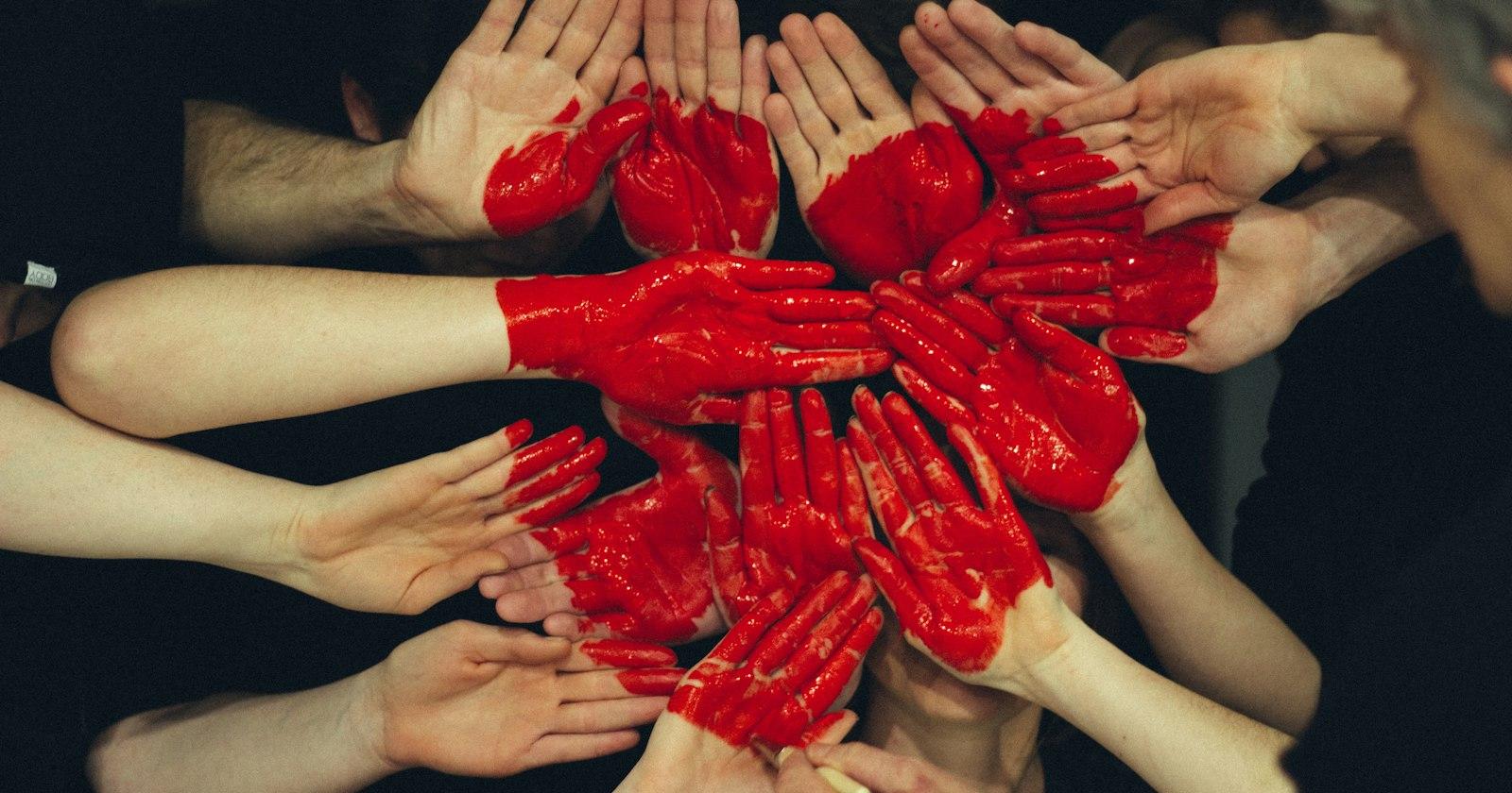 Hands painted red, held together to form a heart